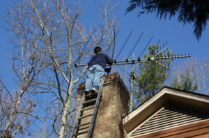 Sweep cleaning chimney on ladder