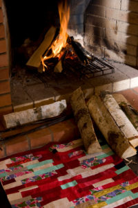 Seasoned firewood in front of a  lit fireplace