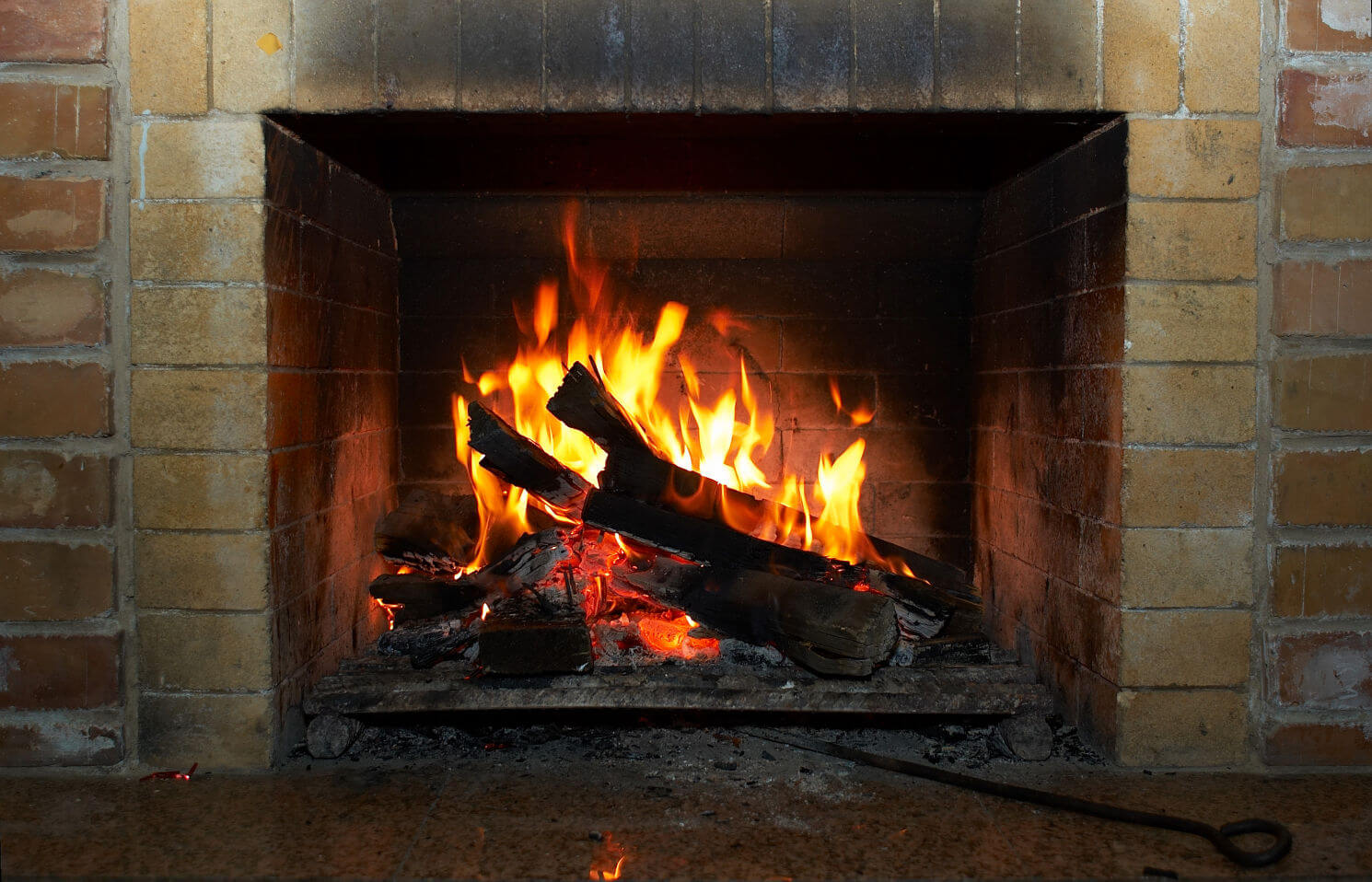Trust us for Firebox repairs and rebuilds-Close up of wood burning in fireplace with brick surround