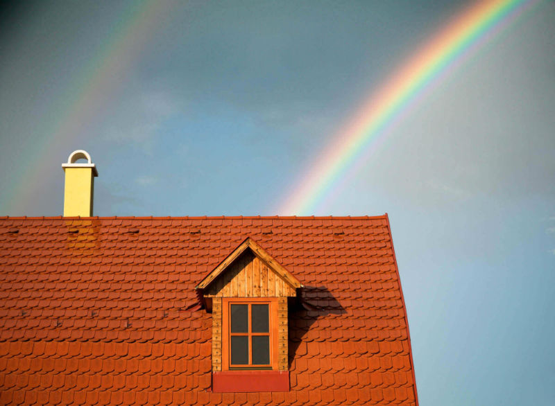 Red roof house with chimney at the end of a rainbow