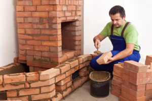 mason repairing a red brick fireplace