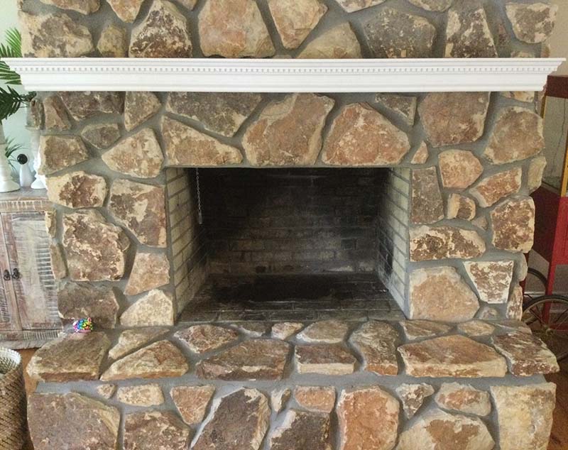A masonry fireplace box inside a brown rock chimney