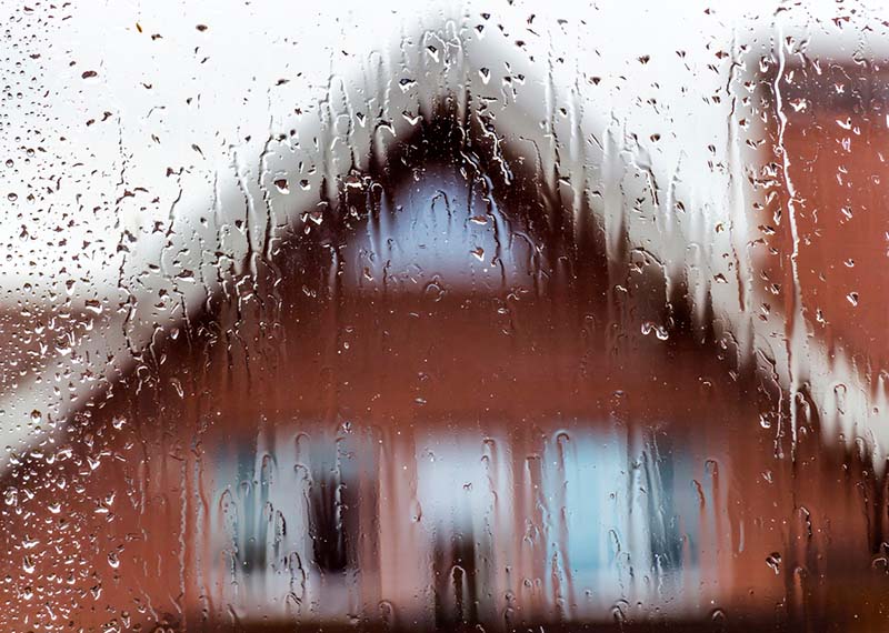 View of a red brick house from rainy window.