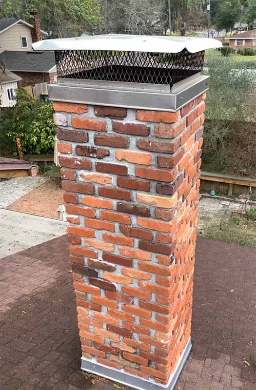 Stock photo -chimney restoration - Hudson's Chimney Masonry chimney flue masonry chase with custom outside mount cap with houses in the background.