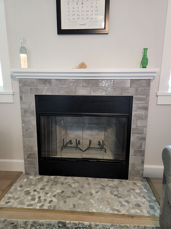 Majestic Royalton 36in insert with tile surround and river rock hearth.  The mantel has a green and clear vase and calendar handing on the wall above.